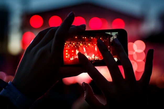 El visitante del concierto graba un video en un teléfono inteligente.