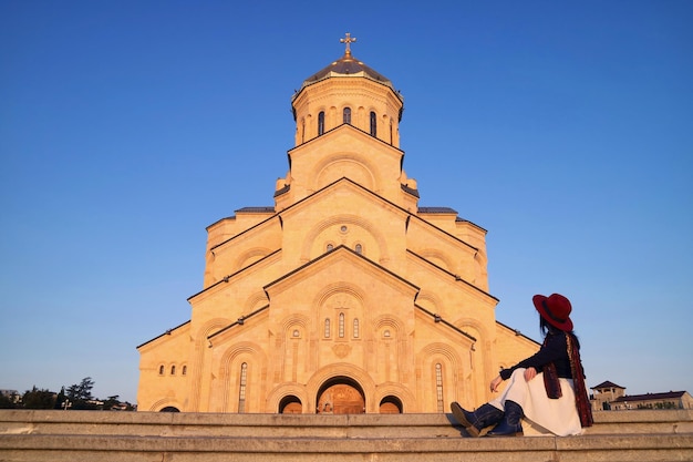 Visitante feminina sentada na escadaria da Catedral da Santíssima Trindade de Tbilisi, Geórgia