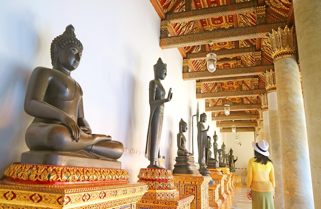 Visitante impressionado com antigas imagens de Buda consagradas no Templo de Mármore em Bangkok, Tailândia
