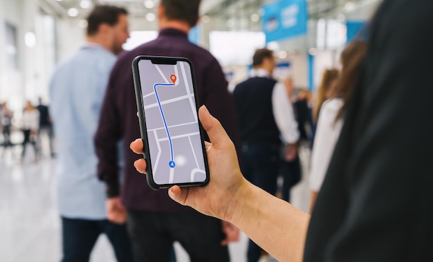 Visitante que usa la aplicación de navegación de mapas GPS en la pantalla del teléfono inteligente para obtener la dirección a la dirección de destino en la imagen conceptual de la ciudad, los viajes y la tecnología