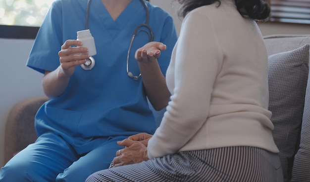 Un visitante de salud con tableta explicando a una mujer mayor cómo tomar pastillas