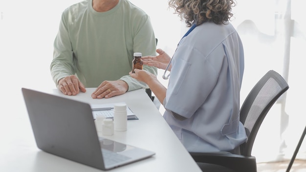 Un visitante de salud con tableta explicando a una mujer mayor cómo tomar pastillas