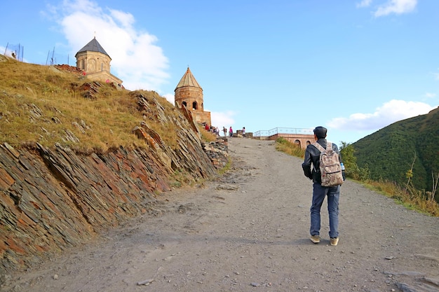 Visitante subindo para a igreja medieval gergeti trinity na cidade de stepantsminda kazbegi georgia