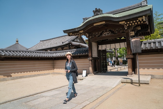 una visitante visitando y caminando por la entrada de una arquitectura tradicional japonesa.