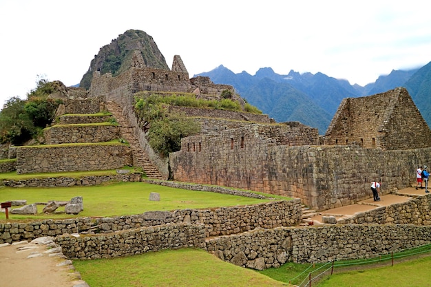 Visitantes que exploran las ruinas incas antiguas de la fortaleza de Machu Picchu en la región de Cusco de Perú