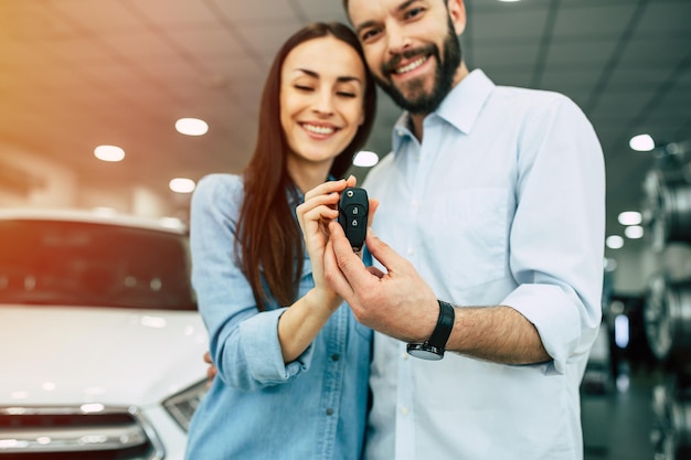 Foto visite a concessionária feliz jovem casal escolhe e compra um carro novo para a família