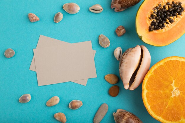 Visitenkarte aus grauem Papier mit reifen geschnittenen Papaya, Orange, Muscheln sea