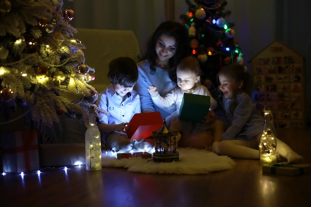 Vispera de Año Nuevo. La casa está decorada para las vacaciones. Árbol de Navidad elegantemente vestido con guirnalda y una familia con regalos y una sorpresa.