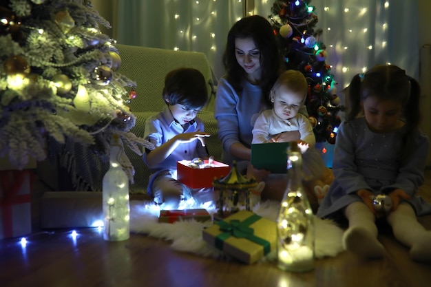 Vispera de Año Nuevo. La casa está decorada para las vacaciones. Árbol de Navidad elegantemente vestido con una guirnalda y una familia con regalos y una sorpresa.