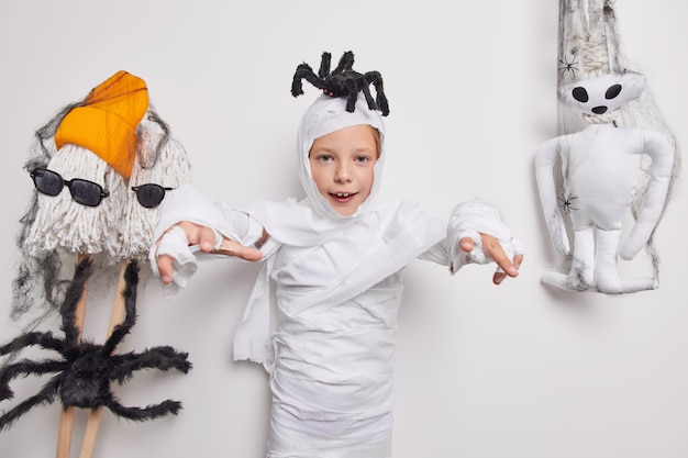 Víspera de Todos los Santos. El fantasma espeluznante del niño pequeño hace truco o trato tiene una araña en la cabeza y dice que te comeré listo para celebrar poses de fiesta en blanco