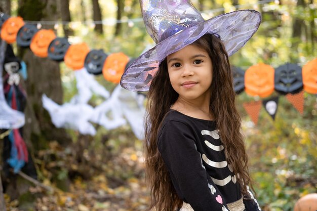 Víspera de Todos los Santos. retrato de una linda chica árabe disfrazada de halloween y sombrero de bruja al aire libre