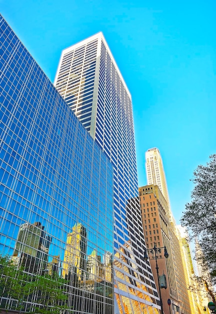 Vista de abajo hacia arriba de los rascacielos de Manhattan. Nueva York, Estados Unidos. En un clima soleado. Rascacielos se refleja en un vaso de otro rascacielos.