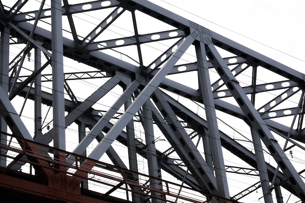 Vista de abajo hacia arriba de la sección del puente de armadura de ferrocarril contra el fondo del cielo nublado