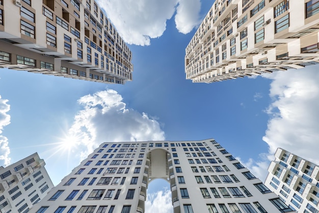 Vista desde abajo en el cielo azul con nubes de un gran complejo residencial moderno de rascacielos con arco