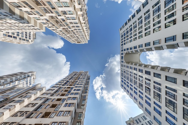 Vista desde abajo en el cielo azul con nubes de un gran complejo residencial moderno de rascacielos con arco