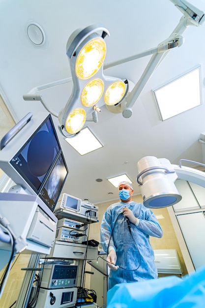 Foto vista desde abajo sobre el cirujano que realiza la operación equipo moderno en la sala de cirugía con luz brillante