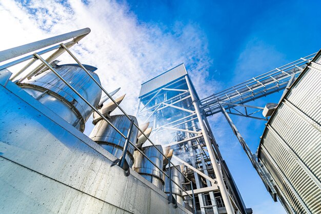 Vista desde abajo sobre elevadores de grano de acero Elevadores de agricultura industrial con grano cosechado Fábrica moderna y actualizada Enfoque selectivo