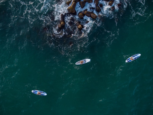 Vista aérea de 3 hombres ejerciendo sup board o Stand Up Paddle en el mar