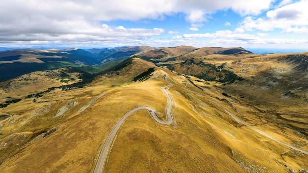 Vista aérea del abejón de la naturaleza en Rumania. Montañas de los Cárpatos, escasa vegetación, camino con coche