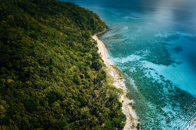 Vista aérea acima do barco solitário atracado em uma ilha deserta tropical remota e isolada com coqueiros de praia de areia branca e lagoa rasa azul turquesa Conceito de paraíso exótico de viagem