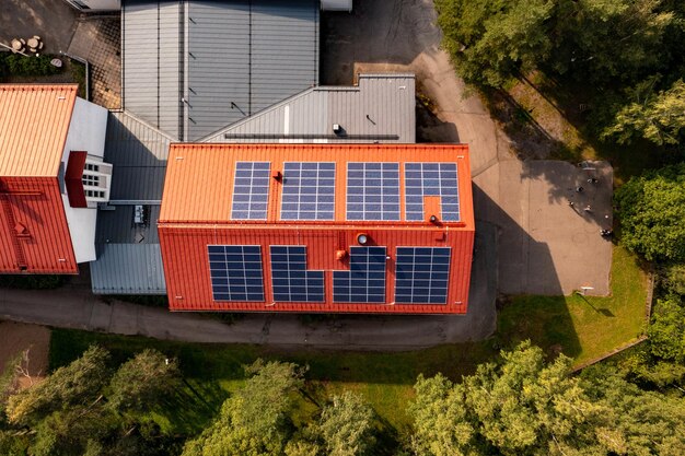 Foto vista aérea acima dos painéis solares no telhado de um edifício vermelho - de cima para baixo, foto de drone