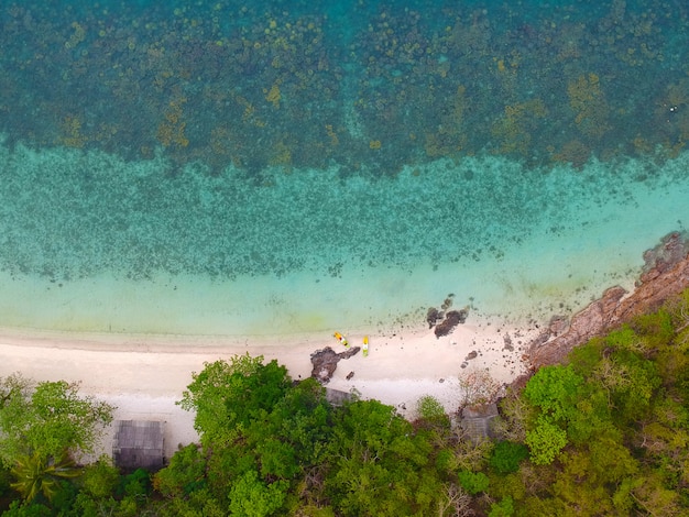 Vista aérea del arrecife de coral y la casa junto al mar con ancla de kayak cerca de un arrecife