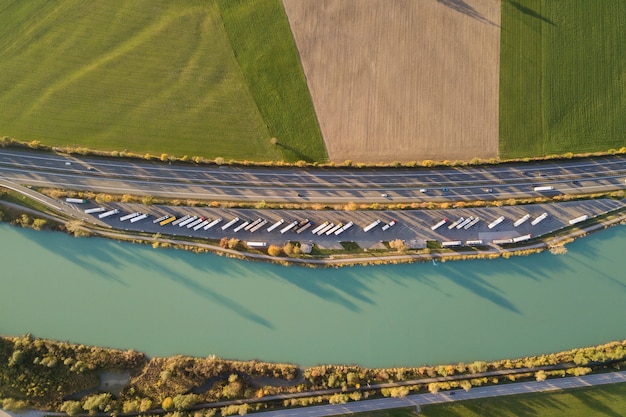 Vista aérea de arriba a abajo de la carretera interestatal con tráfico rápido y estacionamiento con camiones estacionados.