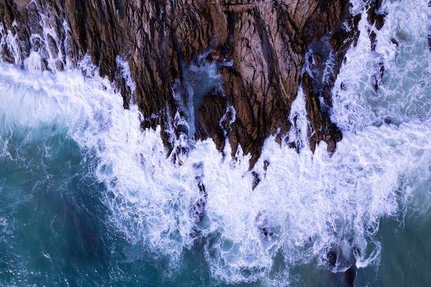 Vista aérea de arriba hacia abajo la gran ola de la orilla del mar rompiendo en el acantilado de la roca Hermosa superficie del mar oscuro en un día soleado de verano de fondo Increíble vista superior del paisaje marino de la costa en Phuket, Tailandia