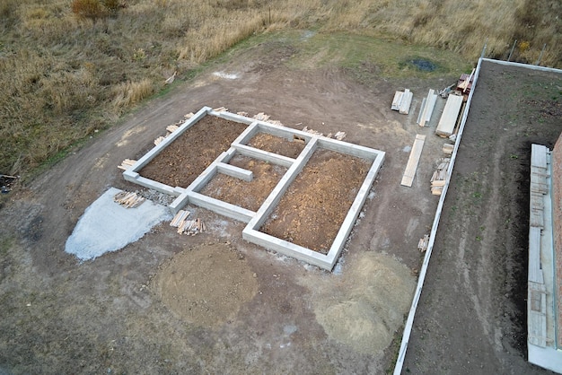 Vista aérea de arriba hacia abajo de las obras de construcción de los cimientos de hormigón de la nueva casa en el sitio de construcción