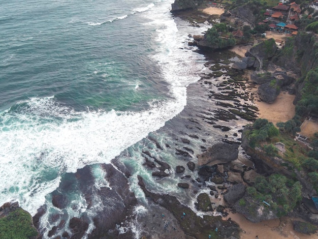 Vista aérea de arriba hacia abajo de las olas gigantes del océano rompiendo y haciendo espuma en la playa de coral