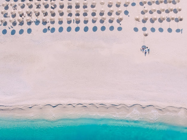 Vista aérea de arriba a abajo a la playa con sombrillas y tumbonas a orillas del hermoso mar turquesa.