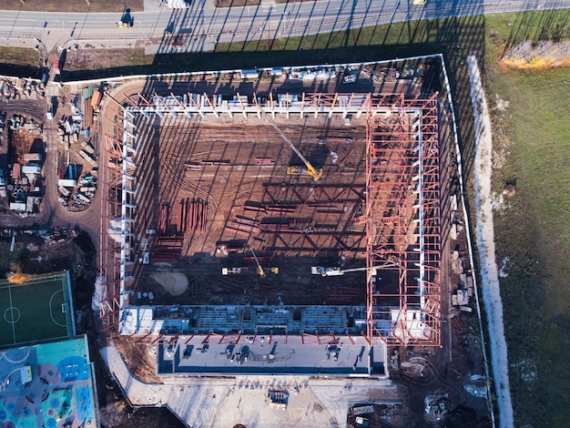 Vista aérea de arriba hacia abajo del sitio de construcción con grúas de camión y elementos del marco de metal.