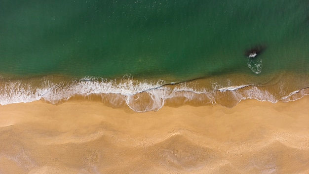 Foto vista aérea de arriba hacia abajo de suaves olas en la playa.