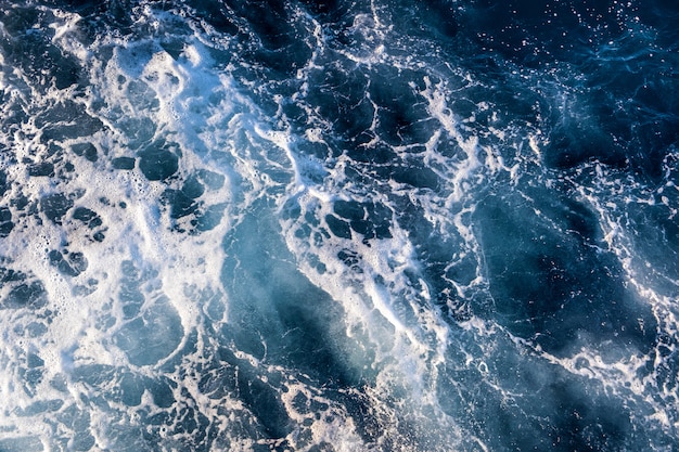 Vista aérea de arriba hacia abajo de la superficie del agua de mar. Textura de ondas de espuma blanca como fondo natural.