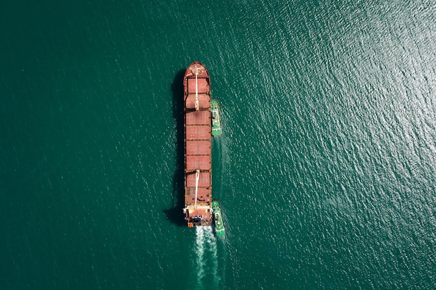 Foto vista aérea de arriba remolcador tirando barco de petróleo rojo al muelle seco del astillero reparación y mantenimiento en el mar