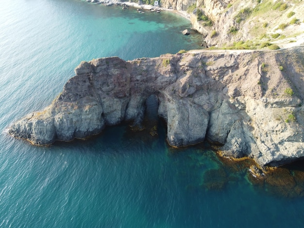 Vista aérea desde arriba sobre el mar azul y las costas rocosas volcánicas pequeñas olas en la superficie del agua en movimiento
