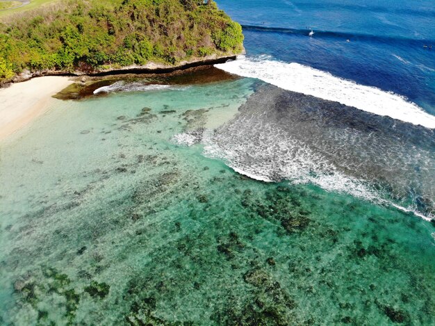 Vista aérea de un asombroso paisaje natural con acantilado rocoso en la costa arenosa de Bali
