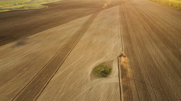 Foto vista aérea con un avión no tripulado de un tractor arando la tierra en el campo al atardecer