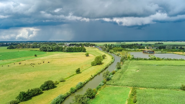 Vista aérea de aviones no tripulados de campos verdes y casas de campo cerca del canal desde arriba, típico paisaje holandés, Holanda, Países Bajos