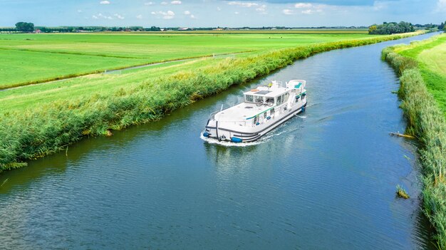 Vista aérea de aviones no tripulados de la casa flotante en el canal y el paisaje campestre de Holanda desde arriba, viaje familiar en barcaza y vacaciones en Holanda