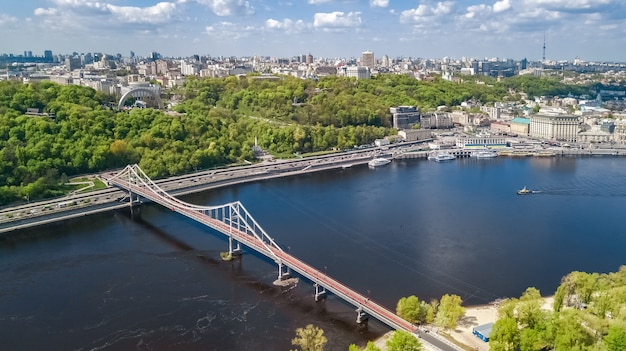 Vista aérea de aviones no tripulados del puente del parque peatonal, el río Dnieper y el paisaje urbano de Kiev desde arriba, ciudad de Kiev, Ucrania