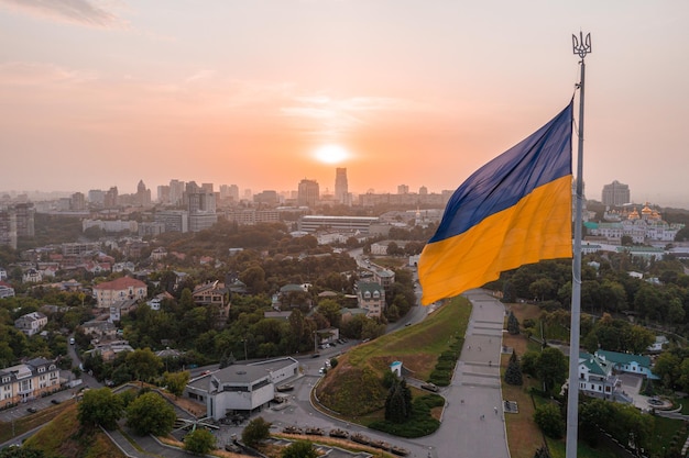 Vista aérea de la bandera de Ucrania ondeando en el viento contra la ciudad de Kiev