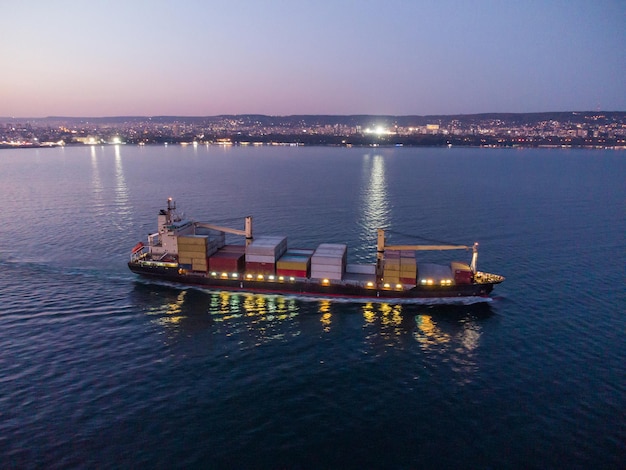 Vista aérea del barco de contenedores de carga en el mar por la noche