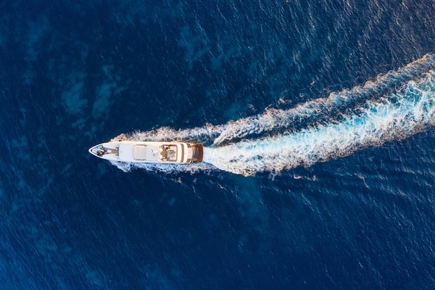 Vista aérea del barco flotante en el mar Adriático azul en un día soleado Barco rápido en la superficie del mar Paisaje marino desde el dron Imagen de viaje