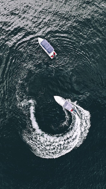 Foto vista aérea de un barco a motor moderno cerca de un yate blanco en la superficie del mar durante el día foto