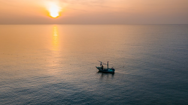 Vista aérea del barco de pesca solitario silueta en el mar durante el amanecer de mañana