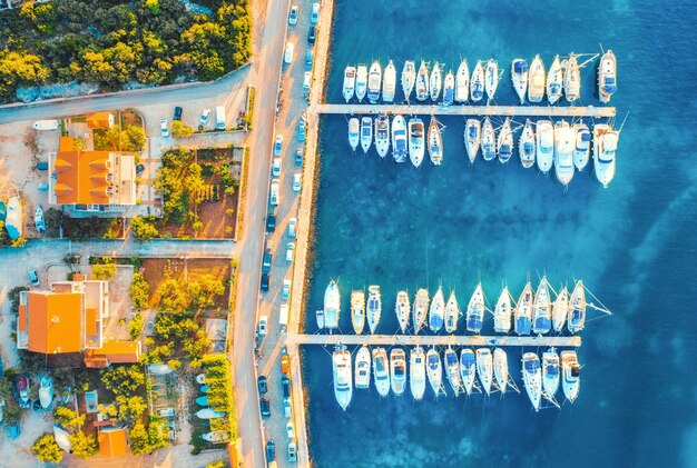 Vista aérea de barcos y yates en el puerto en la hermosa ciudad vieja al atardecer en Croacia en verano Paisaje con edificios con techos naranjas lanchas en el puerto mar azul claro coches carretera Vista superior