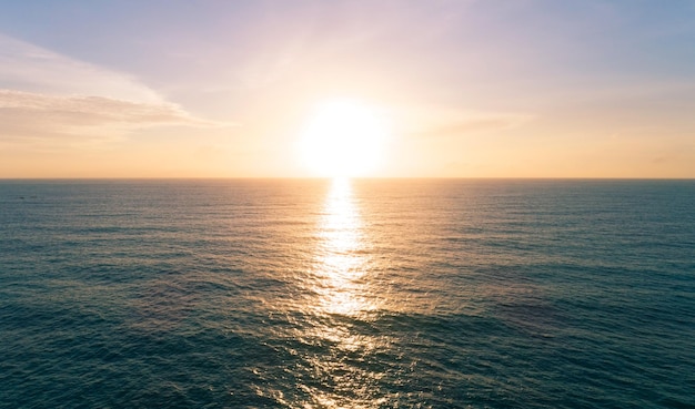Vista aérea bela vista do pôr do sol sobre a superfície do mar bela onda céu incrível luz do pôr do sol ou nascer do sol sobre a praia do mar com ondas quebrando na costa arenosa.