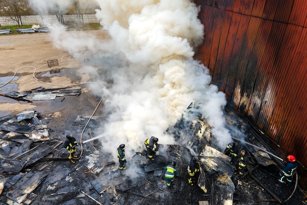 Foto vista aérea de bomberos luchando con fuego cerca de la antigua fábrica de biulding en zona industrial.