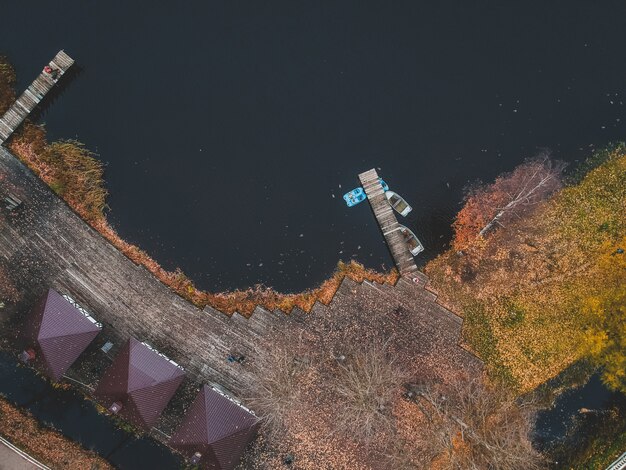 Vista aérea del bosque y el lago azul. Casa de sauna a orillas del lago. Muelle de madera con barcos de pesca. San Petersburgo, Rusia.